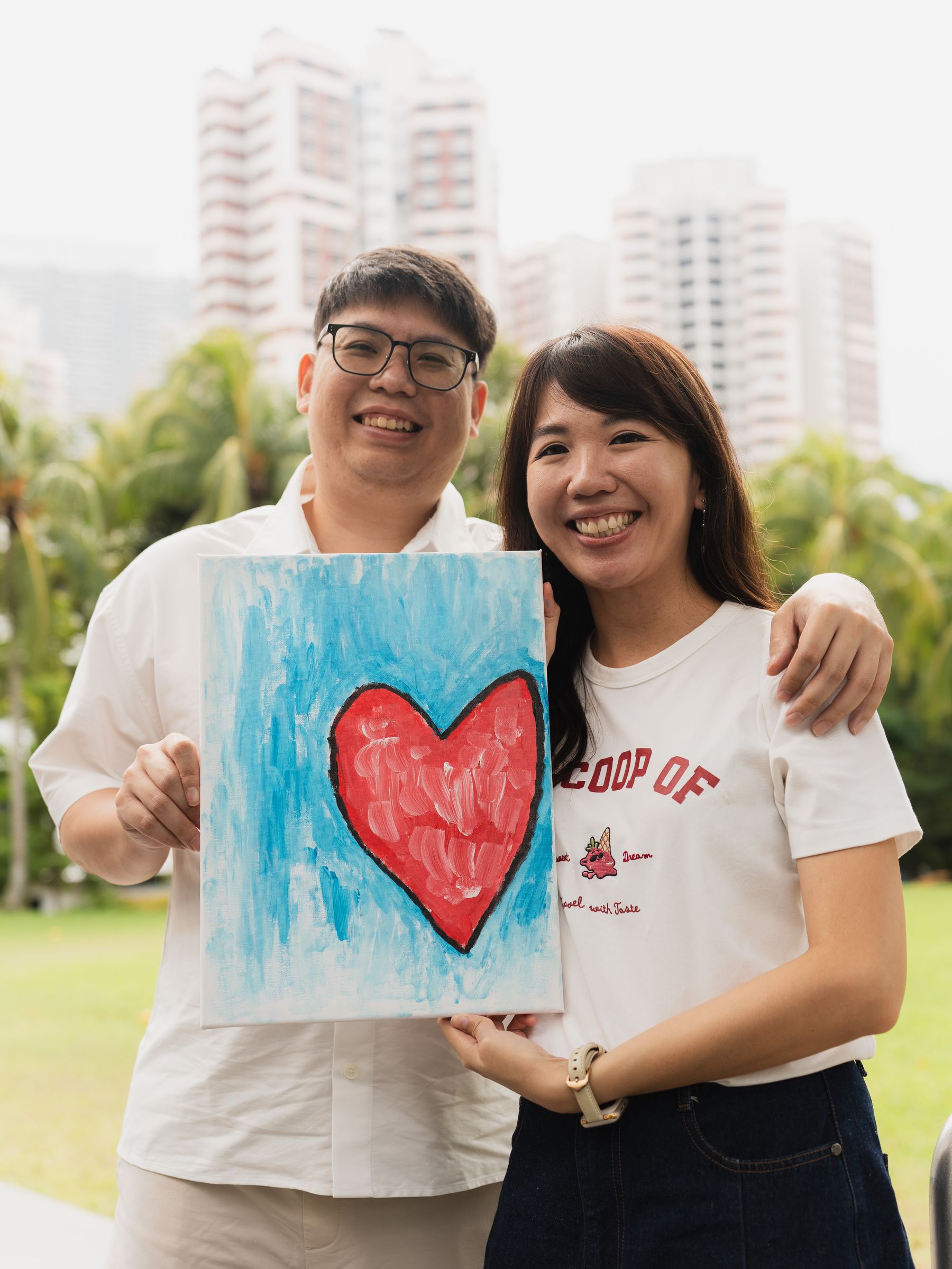 Couple holding up their finished painting outdoors